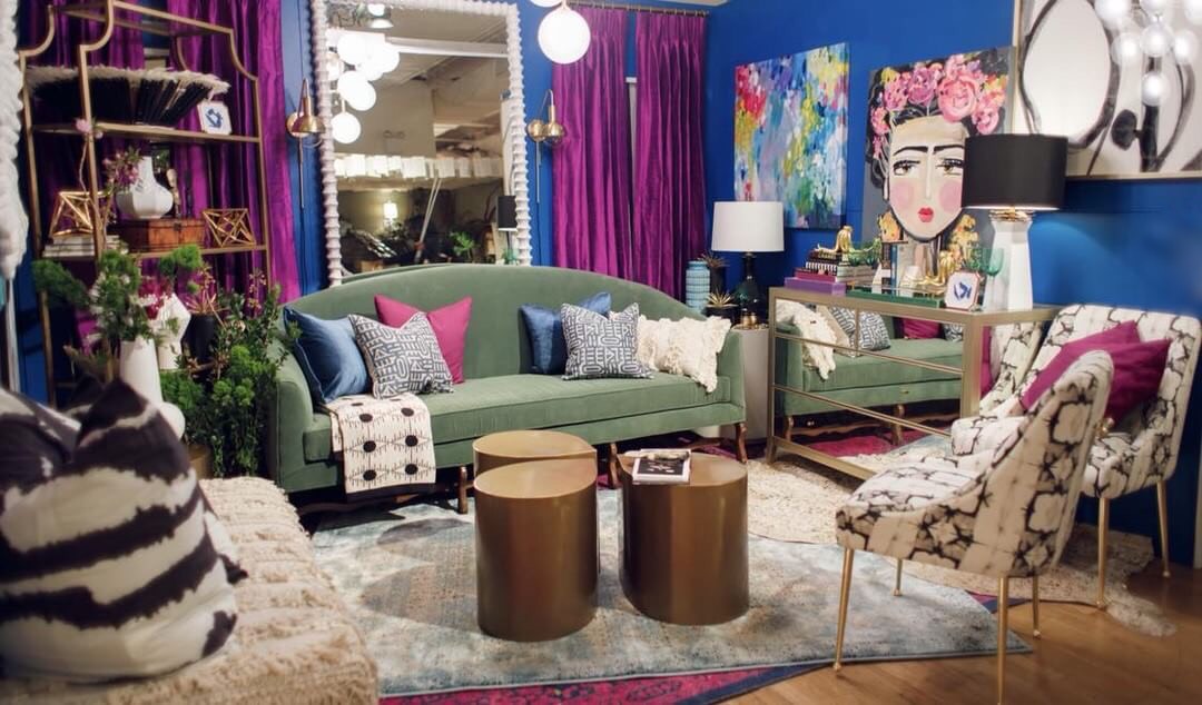 Vignette with bright blue rugs and purple drapes and a velvet sofa