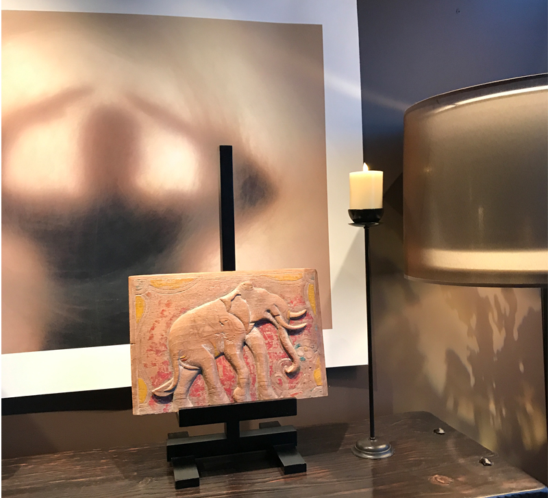 Elephant sculpture on console with floor lamp and candle