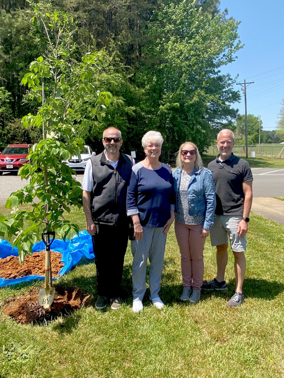 (from left to right): Conrad Kerley, vice president of leather & manufacturing operations; Jean Morgan, retiree; Cheryl Sigmon, vice president of merchandising & product development BY; and Craig Young, president of BY. Employees came together to plant a Dogwood tree in honor of Jean Morgan, who retired at the end of April after 43 years with the company.